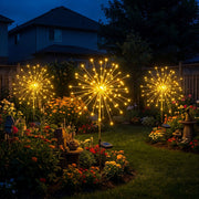 Solar starburst garden stake lights glowing in a flower bed