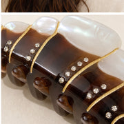 Close-up of gold ridges and rhinestone-style accents on croissant hair claw
