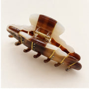 Open croissant hair claw showing spring hinge and rounded teeth