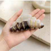 Large croissant hair claw held in hand for scale