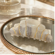 Pearl cream croissant hair claw on a vanity mirror tray